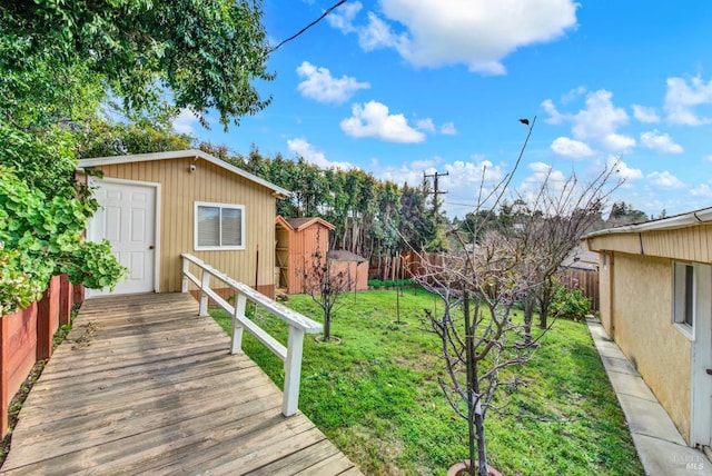 view of yard with a storage shed, a fenced backyard, a wooden deck, and an outbuilding