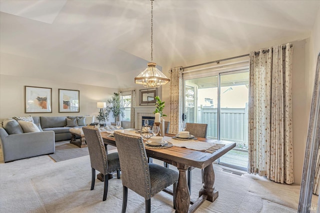 dining space featuring lofted ceiling, light colored carpet, visible vents, and a tile fireplace