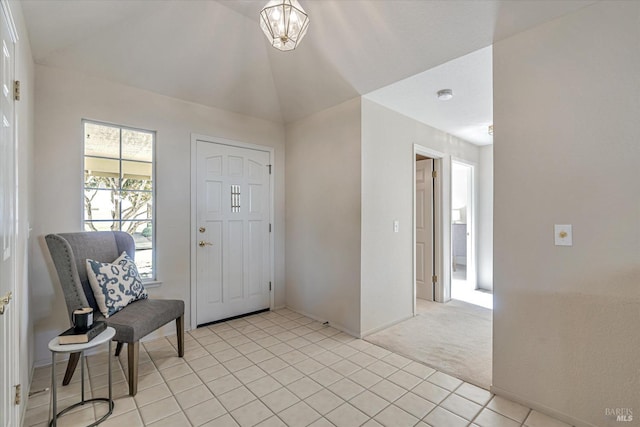 foyer entrance featuring light tile patterned floors, lofted ceiling, and light colored carpet