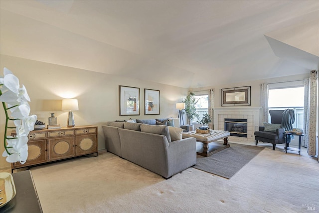 living area with lofted ceiling, carpet floors, and a tile fireplace