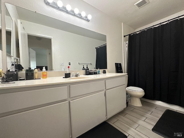 bathroom featuring a textured ceiling, vanity, and toilet