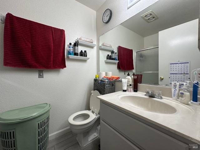 bathroom with toilet, vanity, and a shower with shower door