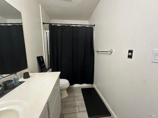 bathroom featuring toilet, a textured ceiling, and vanity