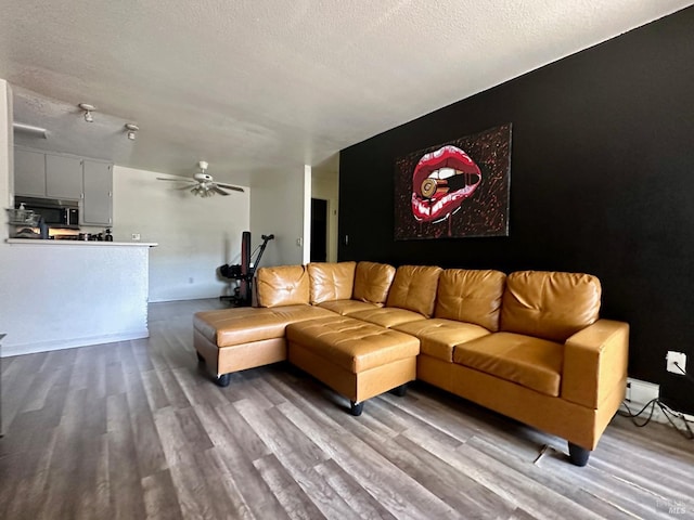 living room featuring a textured ceiling, light wood-type flooring, and ceiling fan