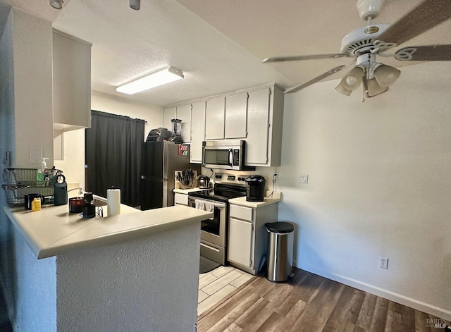 kitchen with kitchen peninsula, a textured ceiling, light hardwood / wood-style flooring, stainless steel appliances, and ceiling fan