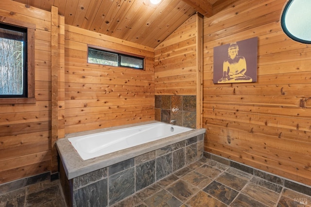 bathroom featuring vaulted ceiling, a bathtub, wood walls, plenty of natural light, and wooden ceiling