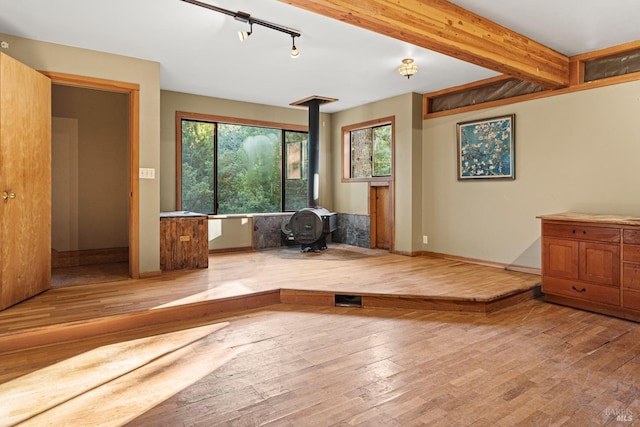 exercise area with track lighting, light hardwood / wood-style floors, and a wood stove