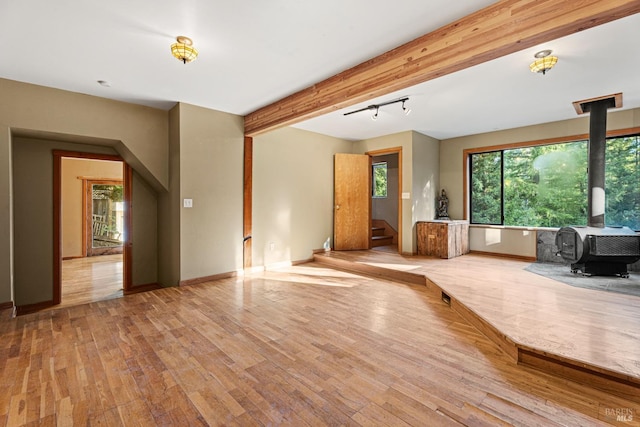 unfurnished living room featuring light hardwood / wood-style floors, beamed ceiling, cooling unit, and a wood stove