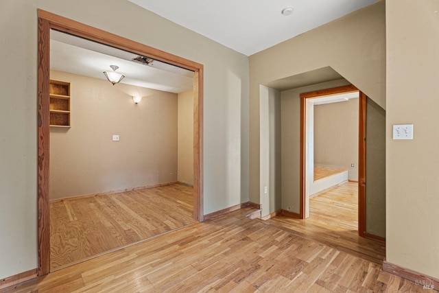 spare room with baseboards and wood finished floors