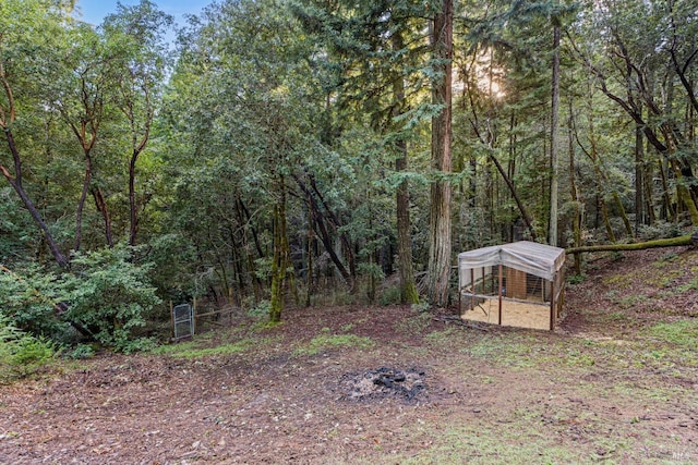 view of yard with exterior structure, an outdoor structure, and a wooded view