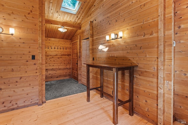 interior space with wooden ceiling, wood walls, and vaulted ceiling with skylight