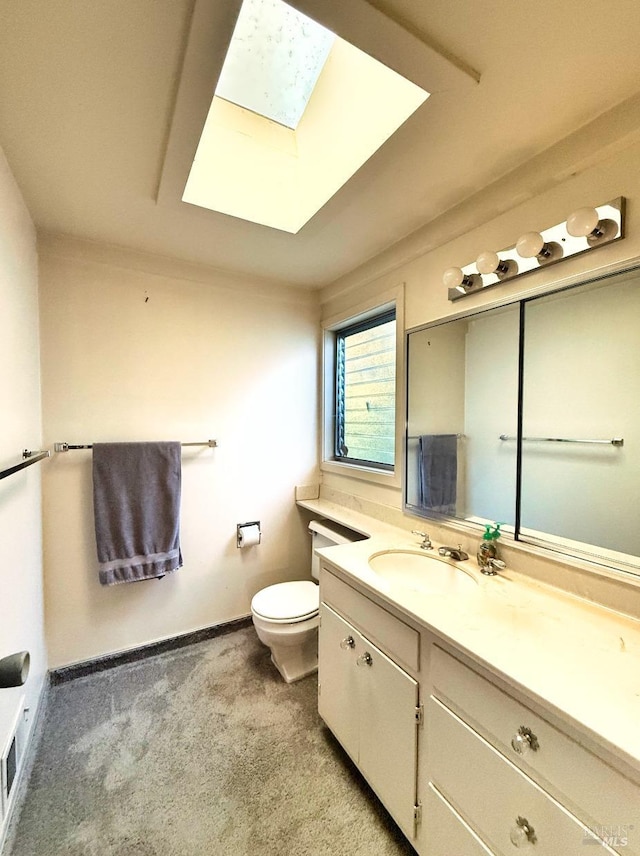 bathroom with toilet, vanity, and a skylight