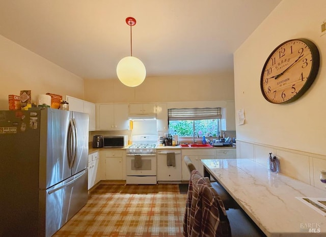 kitchen featuring white appliances, pendant lighting, white cabinetry, sink, and light stone counters