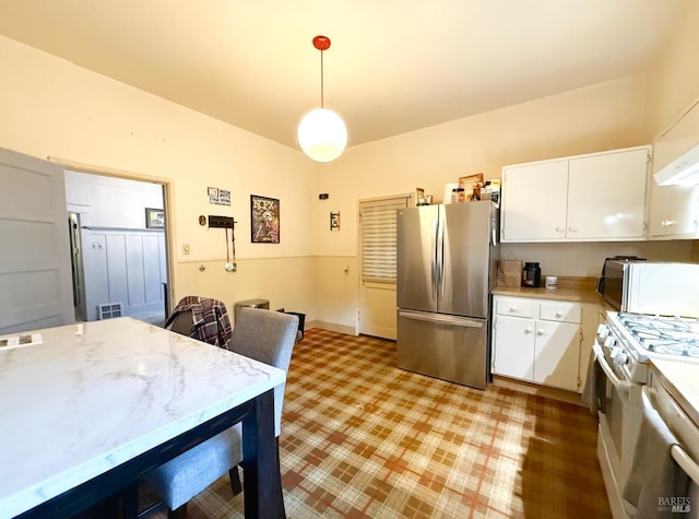 kitchen with hanging light fixtures, white cabinets, stainless steel refrigerator, and white range with gas cooktop