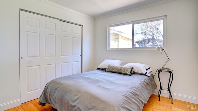 bedroom with light hardwood / wood-style floors, ornamental molding, and a closet