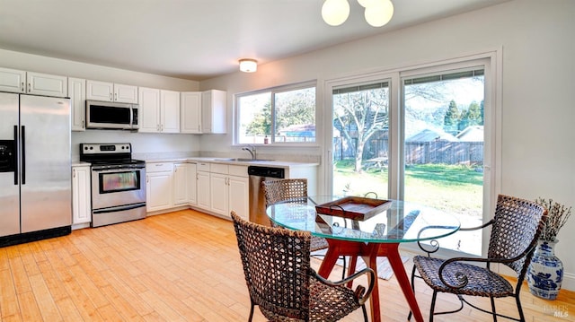 kitchen featuring sink, stainless steel appliances, light hardwood / wood-style floors, and white cabinetry