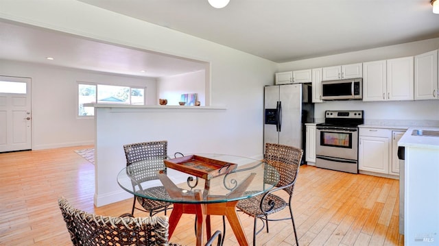 kitchen with stainless steel appliances, light hardwood / wood-style floors, white cabinets, and sink