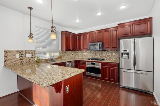 kitchen with sink, kitchen peninsula, backsplash, pendant lighting, and appliances with stainless steel finishes