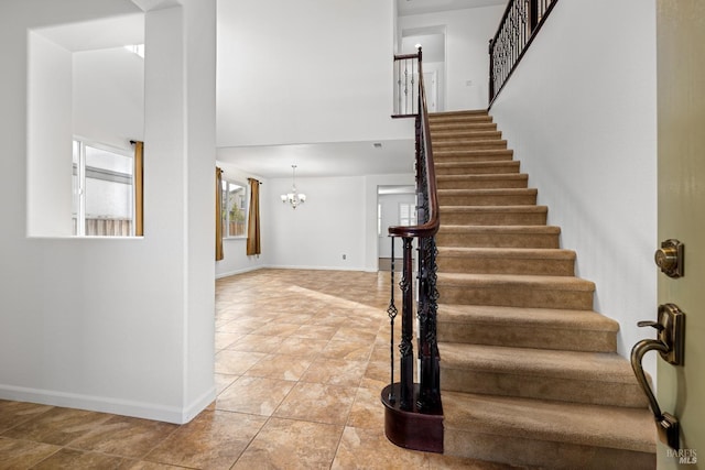 staircase with tile patterned floors and a notable chandelier