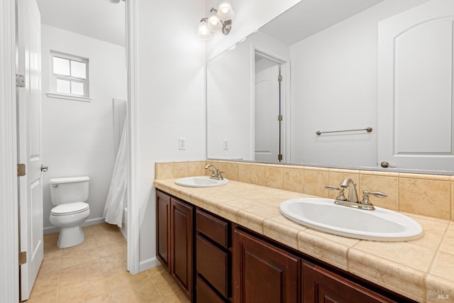 bathroom with toilet, tile patterned flooring, vanity, and decorative backsplash