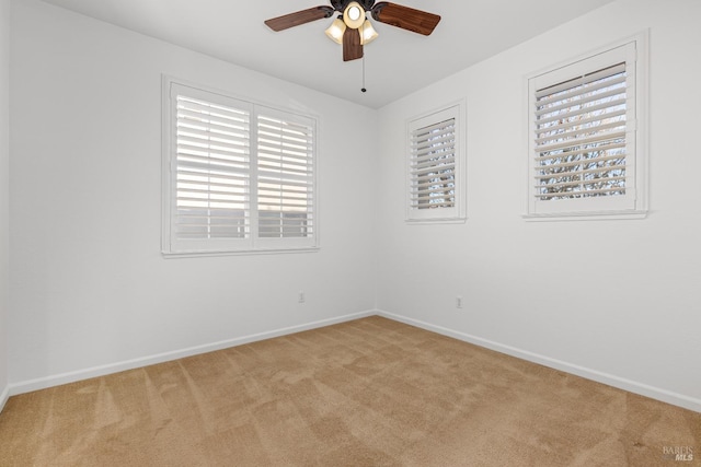 empty room with ceiling fan, a wealth of natural light, and light colored carpet