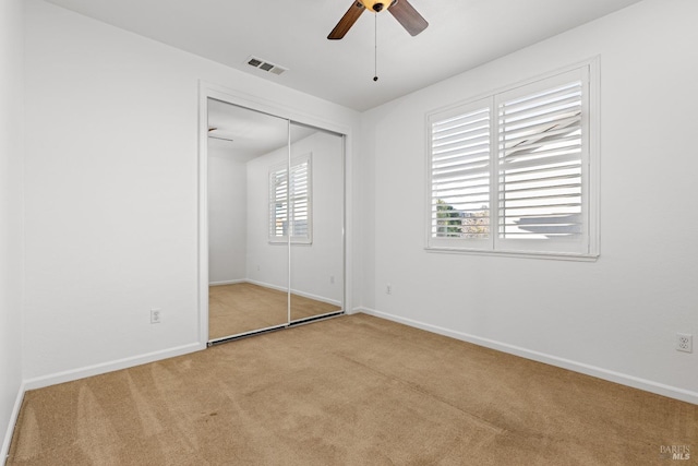 unfurnished bedroom with light carpet, a closet, and ceiling fan