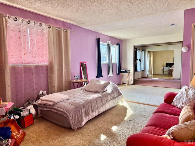 bedroom featuring carpet floors, visible vents, and a textured ceiling