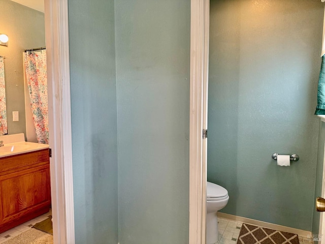 bathroom with toilet, tile patterned flooring, baseboards, and vanity