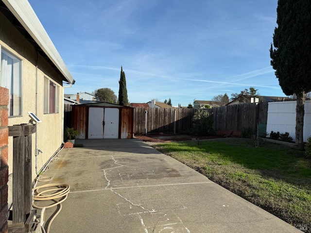 view of yard with a patio, a shed, an outdoor structure, and a fenced backyard