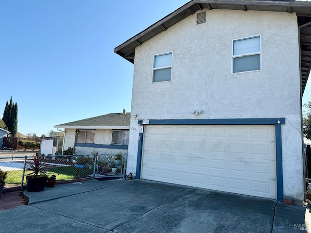 exterior space with a garage, driveway, fence, and stucco siding