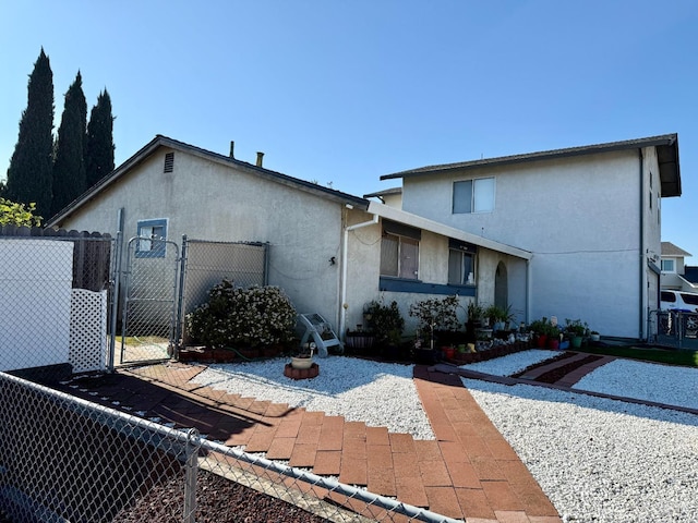 exterior space with a gate, fence, and stucco siding