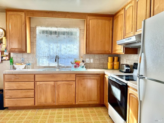 kitchen with light floors, electric range oven, freestanding refrigerator, a sink, and under cabinet range hood