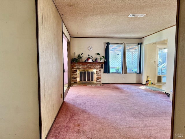 unfurnished living room with carpet, a fireplace, visible vents, and a textured ceiling