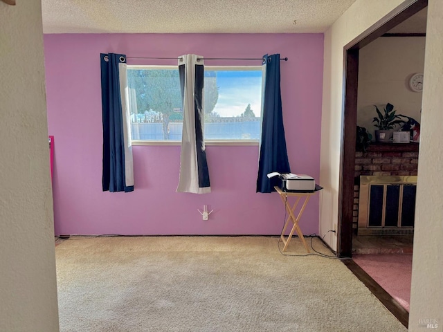 carpeted spare room featuring a fireplace and a textured ceiling