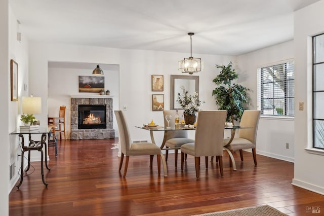 dining room featuring a fireplace, an inviting chandelier, and dark hardwood / wood-style floors