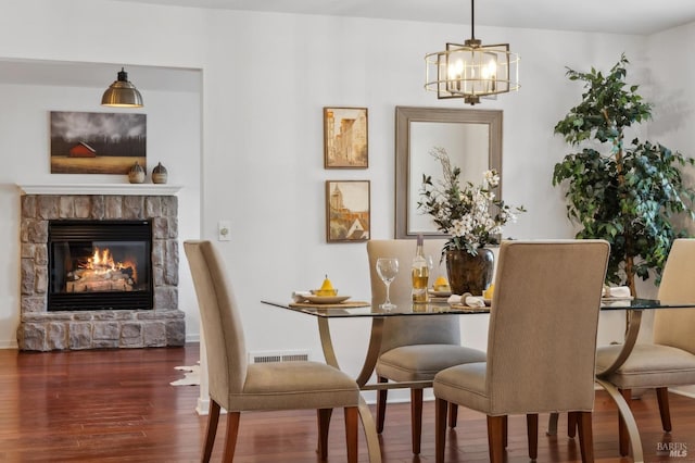 dining area featuring a fireplace, dark wood-type flooring, and a notable chandelier