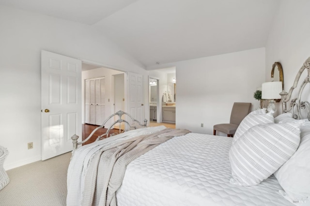 bedroom featuring light colored carpet, connected bathroom, a closet, and lofted ceiling