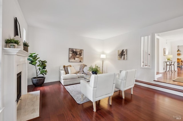 living room with wood-type flooring and a tiled fireplace