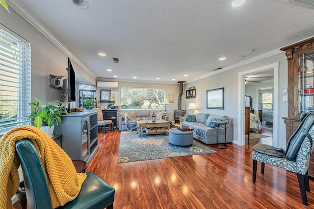 living area with wood finished floors, a wood stove, crown molding, a textured ceiling, and recessed lighting