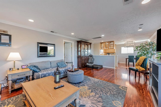 living area with baseboards, visible vents, ornamental molding, and hardwood / wood-style floors