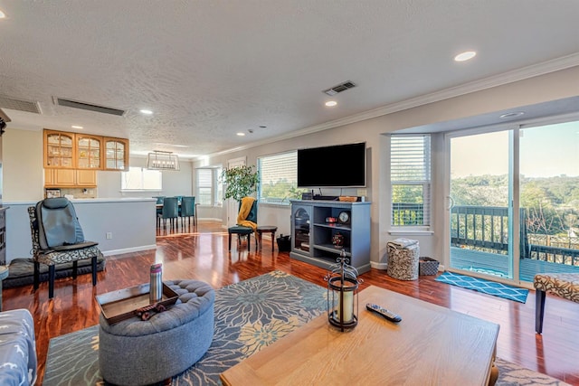 living room featuring visible vents, crown molding, a textured ceiling, and wood finished floors