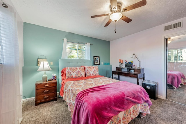 bedroom with carpet floors, visible vents, ceiling fan, and a textured ceiling