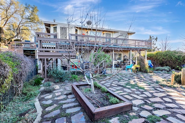 view of community featuring stairway, a patio area, a wooden deck, and a garden