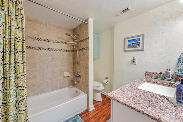 bathroom featuring visible vents, toilet, wood finished floors, shower / bathtub combination with curtain, and a textured ceiling