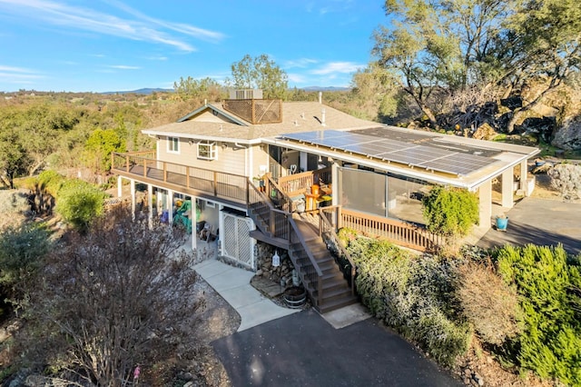 view of front of home with roof mounted solar panels, a deck, and stairs