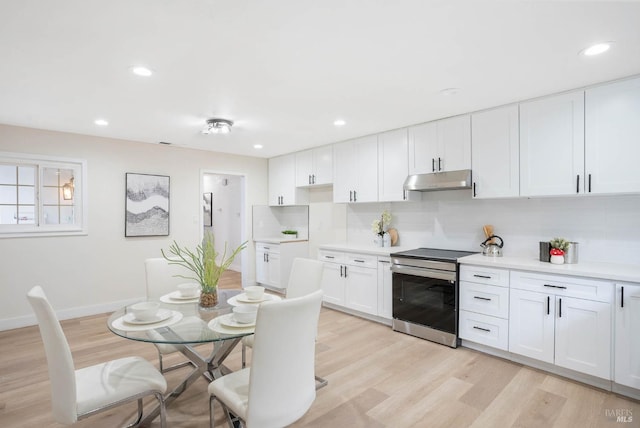 kitchen with stainless steel electric range, white cabinets, tasteful backsplash, and light hardwood / wood-style floors