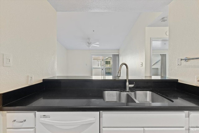 1201 Glen Cove Pkwy Unit 1514, Vallejo, CA 94591 - kitchen with dark countertops, a textured wall, white cabinets, and a sink