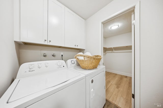 washroom featuring light hardwood / wood-style floors, cabinets, and washer and clothes dryer