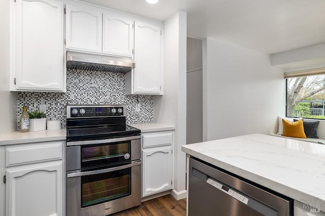 kitchen featuring dark wood-type flooring, dishwasher, range with two ovens, tasteful backsplash, and white cabinetry