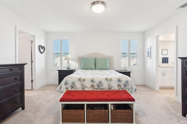 carpeted bedroom with multiple windows and connected bathroom